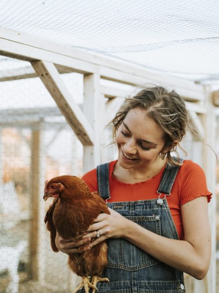 Happy young woman with a brown hen