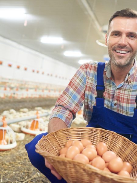 Cheerful farmer with basket full of eggs